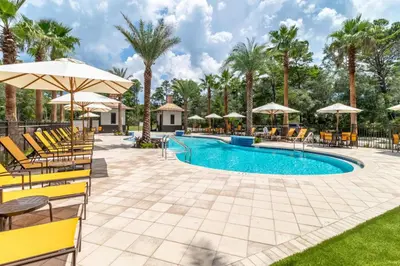 a pool with chairs and umbrellas at a resort at Magnolia Cottages by the Sea by Panhandle Getaways in Watersound Beach