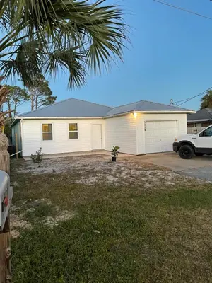 a white house with a car parked in a driveway at House 3 blocks to the beach in Panama City Beach