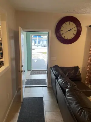 a living room with a couch and a clock on the wall at House 3 blocks to the beach in Panama City Beach