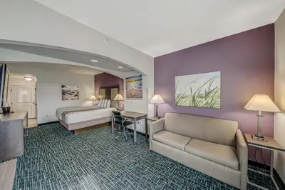 a hotel room with a bed and a couch and a desk at La Quinta by Wyndham PCB Pier Park area in Panama City Beach