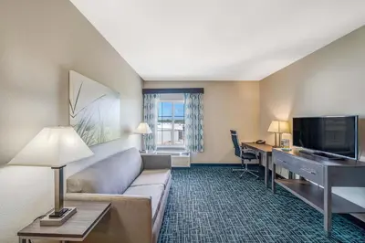 a hotel room with a couch and a desk with a computer at La Quinta by Wyndham PCB Pier Park area in Panama City Beach