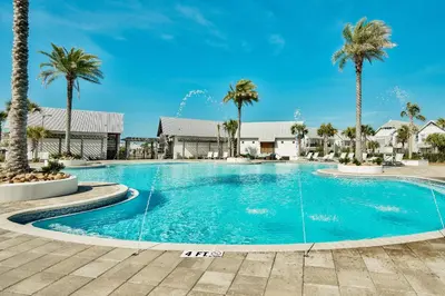 a swimming pool with palm trees in a resort at Prominence on 30A Vacation Homes in Watersound Beach