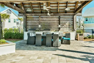 a patio with a wooden pergola with a table and chairs at Prominence on 30A Vacation Homes in Watersound Beach