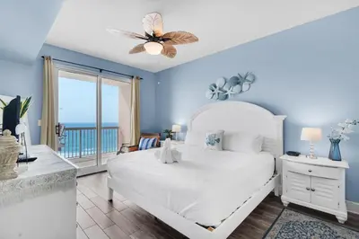 a bedroom with a bed and a balcony with the ocean at Sunrise Beach #910 in Panama City Beach