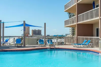 a swimming pool with blue chairs and a building at Sunrise Beach #910 in Panama City Beach