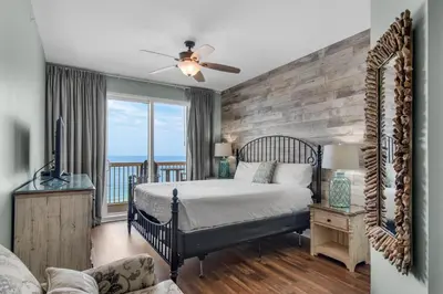 a bedroom with a bed and a view of the ocean at Calypso 1-608 East in Panama City Beach