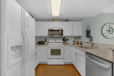 a white kitchen with white cabinets and a refrigerator at Calypso 1-608 East in Panama City Beach