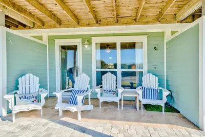 a porch with three white chairs and a table at Sunnyside on the Gulf #3 in Sunnyside