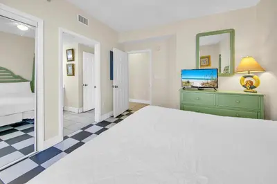 a bedroom with a bed and a dresser and a mirror at Majestic Beach Towers 1-1615 in Panama City Beach