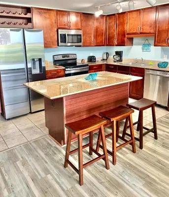 a kitchen with wooden cabinets and a island with stools at LAKETOWN 5 POOLs STEPS TO BEACH FAMILY FRIENDLY in Panama City Beach