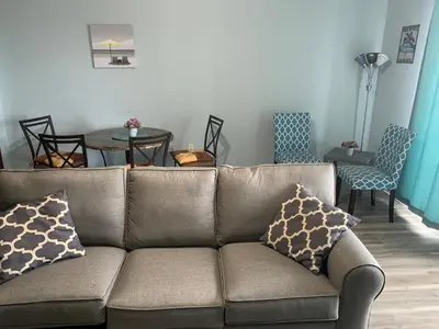 a couch in a living room with a table and chairs at LAKETOWN 5 POOLs STEPS TO BEACH FAMILY FRIENDLY in Panama City Beach