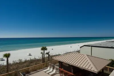 a beach with palm trees and a building and the ocean at Oceanfront Condo with Spacious Balcony - Unit 0306 in Panama City Beach