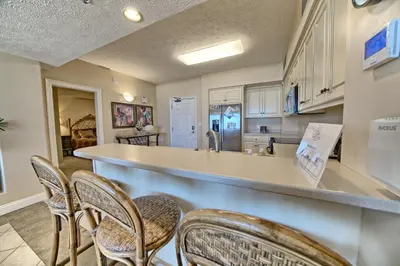 a kitchen with a counter and chairs in a room at Beautiful Beachfront Condo with Pool View - Unit 0203 in Panama City Beach