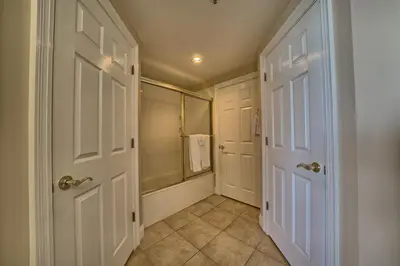 a bathroom with a shower and two white doors at Comfortable High-Rise Condo with Beach Access - Unit 1404 in Panama City Beach