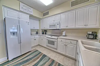a kitchen with white cabinets and a white refrigerator at Roomy Condo with Pool and Beach Access - Unit 0502 in Panama City Beach