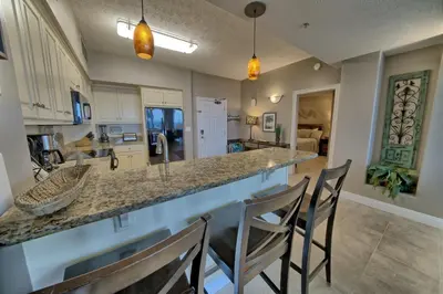 a kitchen with a counter and chairs at a bar at Luxurious High-Rise Condo with Spacious Balcony Facing the Ocean - Unit 1805 in Panama City Beach