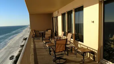 a balcony with chairs and tables and the ocean at Tropical High-Rise Condo with Beachside Pool Access and Free Poolside WiFi - Unit 2004 in Panama City Beach