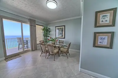a dining room with a table and chairs and a balcony at Luxurious Beachfront Condo with Beachside Pool Access and Free WiFi - Unit 1202 in Panama City Beach