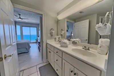 a bathroom with a sink and a mirror and a bedroom at Luxurious Beachfront Condo with Beachside Pool Access and Free WiFi - Unit 1202 in Panama City Beach
