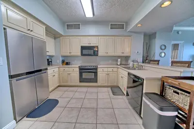 a large kitchen with white cabinets and stainless steel appliances at Luxurious Beachfront Condo with Beachside Pool Access and Free WiFi - Unit 1202 in Panama City Beach