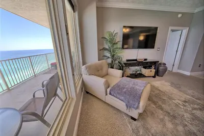 a living room with a couch and a tv and a balcony at Stylish Oceanfront Condo with Beach and Picnic Area Access - Unit 1706 in Panama City Beach