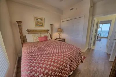 a bedroom with a bed with a red comforter at Stunning 16th Floor Condo with Fitness Center, Hot Tubs, Pools, and Beach Access - Unit 1606 in Panama City Beach