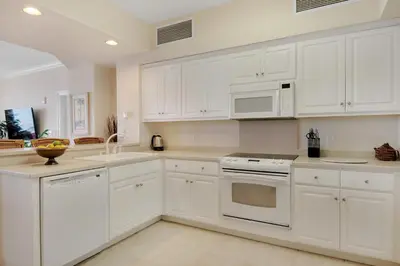 a white kitchen with white cabinets and appliances at Stunning 16th Floor Condo with Fitness Center, Hot Tubs, Pools, and Beach Access - Unit 1606 in Panama City Beach