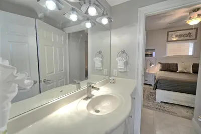 a bathroom with a sink and a mirror and a bed at Gulf Front Condo with Beach Access and Beachside Pool - Unit 1604 in Panama City Beach