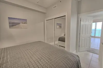 a white bedroom with a bed and a mirror at Gulf Front Condo with Beach Access and Beachside Pool - Unit 1604 in Panama City Beach
