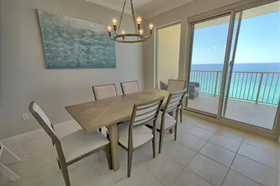 a dining room with a table and chairs and a balcony at Gulf Front Condo with Beach Access and Beachside Pool - Unit 1604 in Panama City Beach
