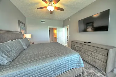 a bedroom with a bed with a ceiling fan and a television at Gulf Front Condo with Beach Access and Beachside Pool - Unit 1604 in Panama City Beach