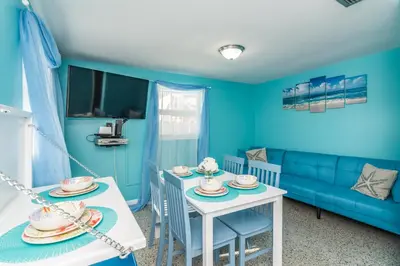 a blue living room with a blue couch and a table and chairs at Villa Paradise, Pet Friendly in Panama City Beach