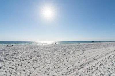 a beach with people sitting on the sand and the ocean at Villa Paradise, Pet Friendly in Panama City Beach