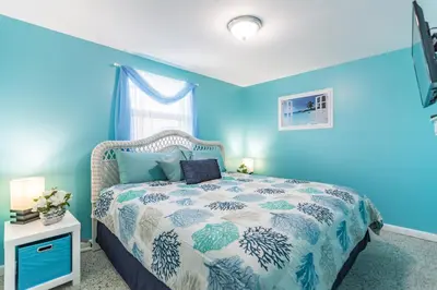 a blue bedroom with a bed and a blue wall at Villa Paradise, Pet Friendly in Panama City Beach