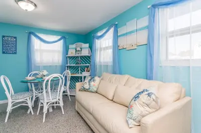 a living room with blue walls and a couch and a table at Villa Serenity, Pet Friendly in Panama City Beach