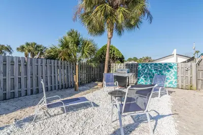 a group of chairs and a table on the beach at Villa Serenity, Pet Friendly in Panama City Beach