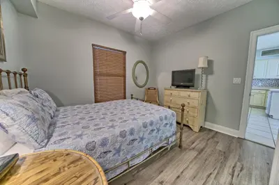 a bedroom with a bed and a tv and a table at Tropical Gulf Front Condo with Picnic Area & Grills - Unit 0802 in Panama City Beach