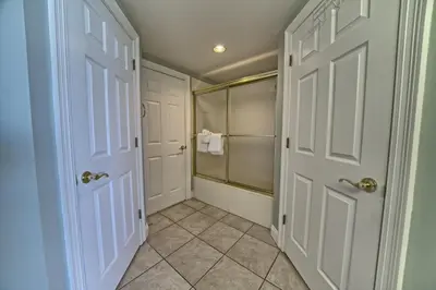 a bathroom with a shower and two white doors at Tropical Gulf Front Condo with Picnic Area & Grills - Unit 0802 in Panama City Beach