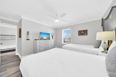 a white bedroom with two beds and a window at Fishers in Panama City Beach