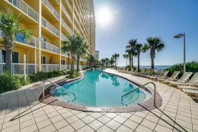 a swimming pool in front of a building with palm trees at Calypso Beach Resort in Panama City Beach