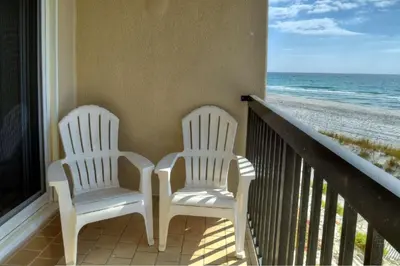 two white chairs sitting on a balcony overlooking the beach at Pinnacle Port C1-203 in Carillon Beach