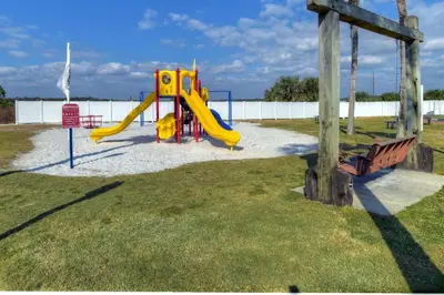 a playground with a yellow slide and a bench at Pinnacle Port C1-203 in Carillon Beach