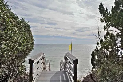 a wooden pathway leading to the ocean with a yellow flag at Seabreeze Cottage #45 in Watersound Beach