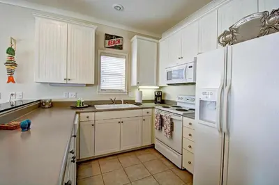 a kitchen with white cabinets and a white refrigerator at Seabreeze Cottage #45 in Watersound Beach