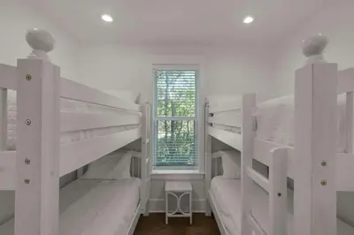 two bunk beds in a white room with a window at Beach Breeze in Watersound Beach