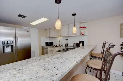 a kitchen with a counter with chairs and a refrigerator at Pinnacle Port C1-302 in Carillon Beach