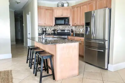 a kitchen with wooden cabinets and a stainless steel refrigerator at Key Largo in Seagrove Beach