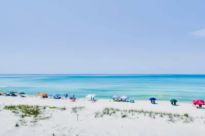 a group of people on a beach with umbrellas at Pinnacle Port B3-307 in Carillon Beach