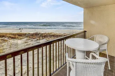 a balcony with a table and chairs and the beach at Pinnacle Port B3-307 in Carillon Beach