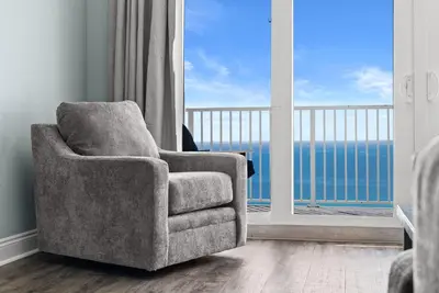 a chair in a room with a large window at Laketown Wharf Remodeled Gulf View Retreat! 3BR Resort Condo with Huge Balcony in Panama City Beach